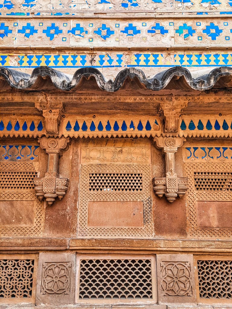 Blue and yellow tiles above a carved wave-shaped eave, Man Singh Palace